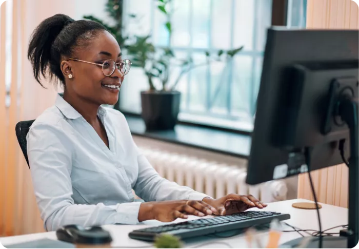 Femme souriante travaillant sur son ordinateur dans un bureau.