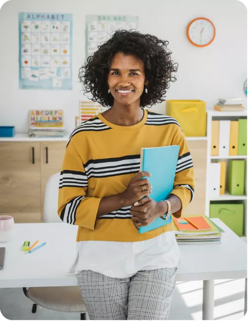 Maitresse d'école assise sur un pupitre avec des documents sous le bras